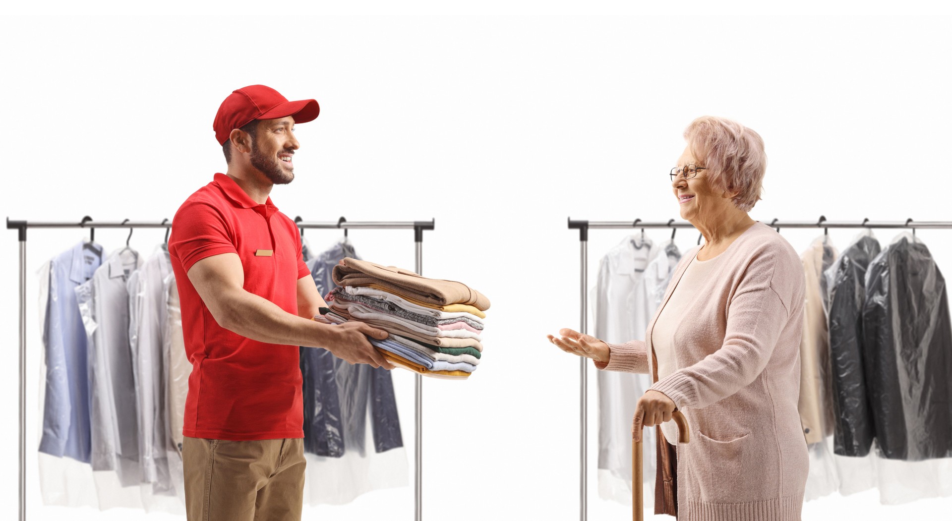 Un travailleur livrant une pile de vêtements pliés du pressing à une dame âgée